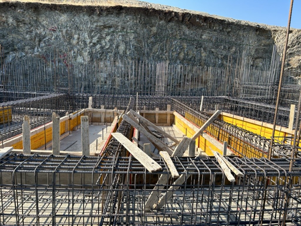 Akra Vista villa under construction — cut into the hillside, formwork rising
