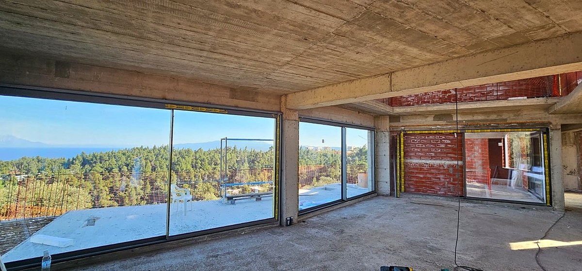 Akra Vista villa under construction — full-height glazing frames the aegean
